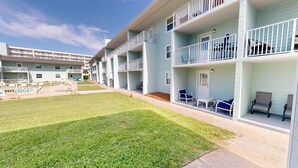 A multi-story building with balconies, a swimming pool, and outdoor seating. - Steps to the Pool 1 Bedroom Sleeps 4 by RedAwning (Fort Walton Beach)