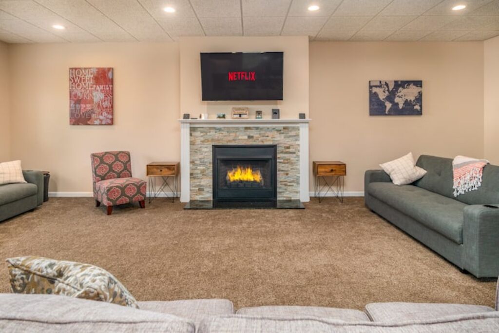 Una sala de estar con chimenea, televisor montado encima y dos sofás.