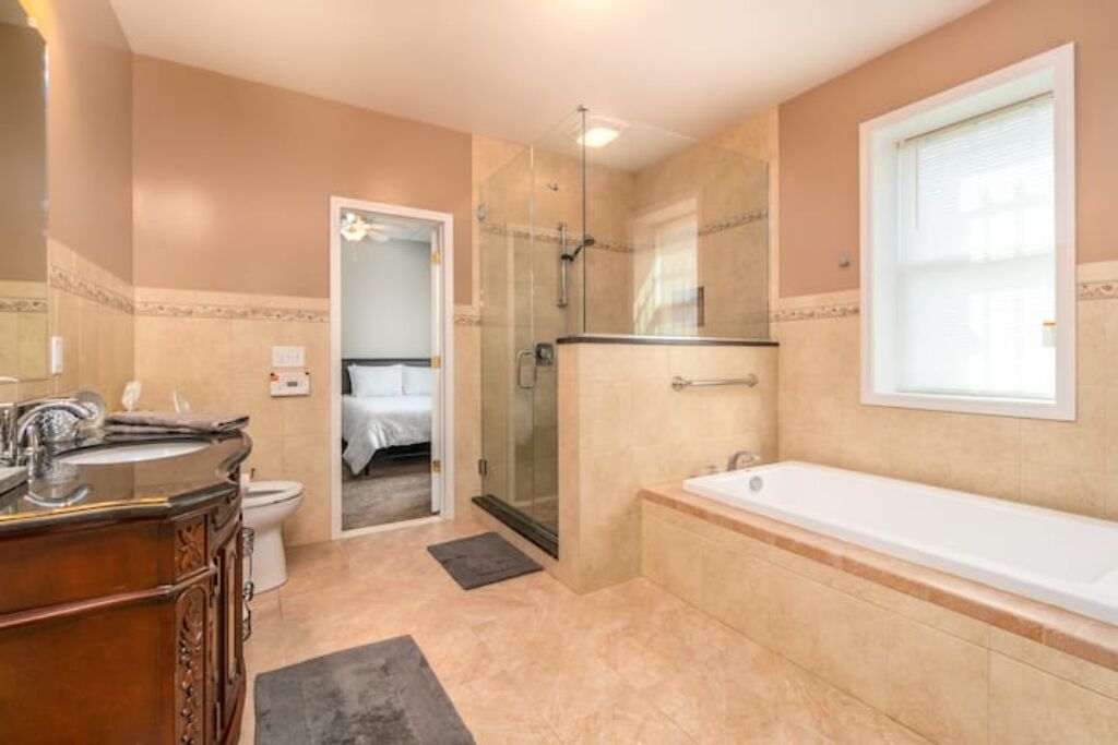 Une salle de bain comprenant une baignoire, une douche à parois de verre, des toilettes et un meuble-lavabo avec un miroir.