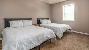 Une chambre avec deux lits, un ventilateur de plafond, une fenêtre et un revêtement de sol en moquette.