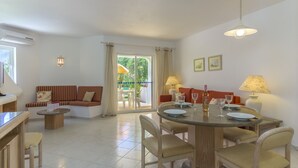 Un salon moderne avec un canapé, une table à manger et des chaises. On y trouve une fenêtre avec des rideaux, une lampe et un ventilateur de plafond.