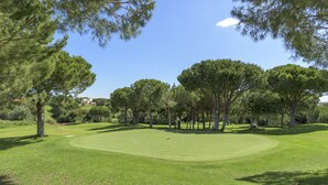 Un parcours de golf bien entretenu, avec un fairway dégagé, des arbres et un bâtiment visible au loin.