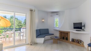Ein Wohnzimmer mit einer Couch, einem Fernseher, einem Kamin und einem Essbereich mit Stühlen und einem Tisch.