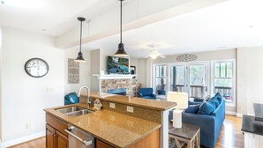 Una cocina moderna con encimeras de granito, electrodomésticos de acero inoxidable e iluminación colgante.