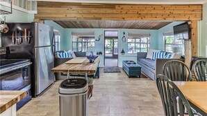 A kitchen with a wooden ceiling, a refrigerator, a stove, and a dining area with a table and chairs. - Fun Weeki Wachee River Boathouse (Weeki Wachee)