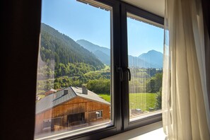 A window with a view of a mountainous landscape, a wooden building, and a clear sky. - 4803 Cirrus 3 (St. Gallenkirch)