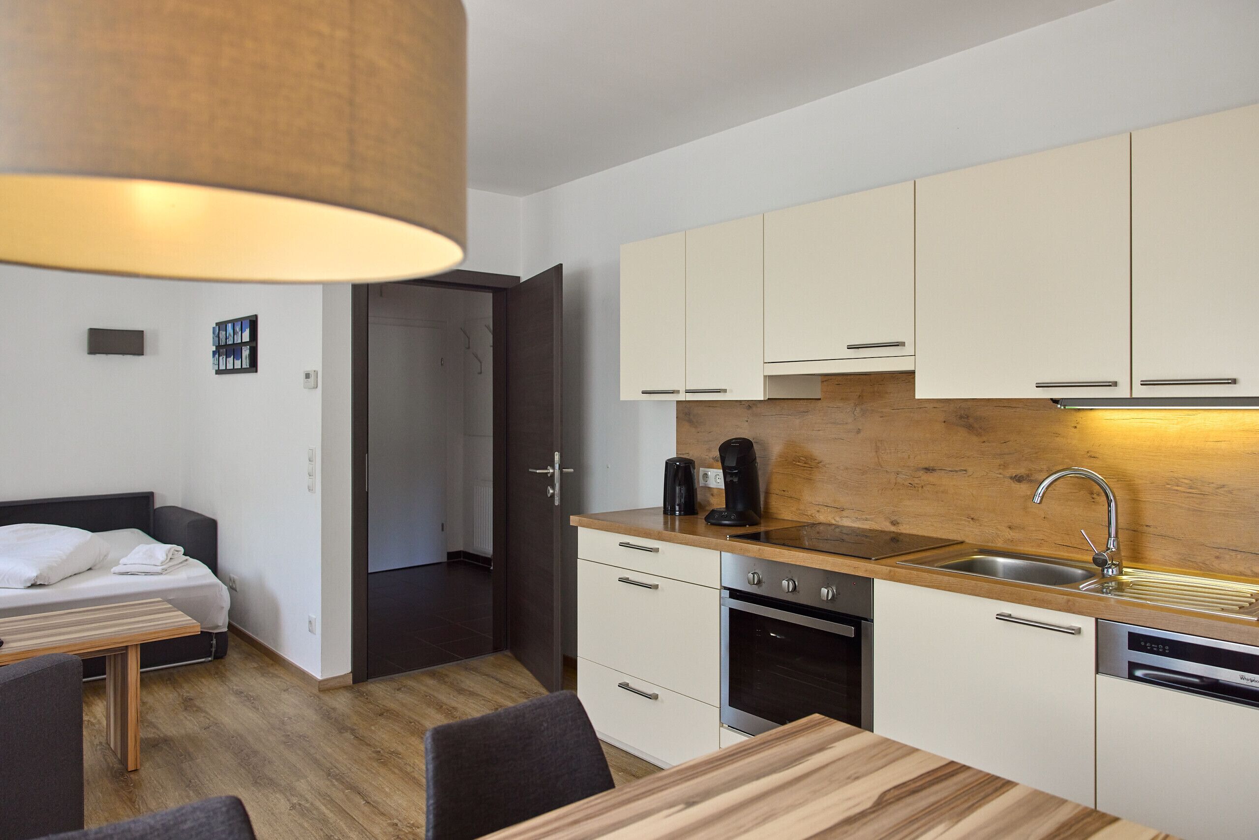 A compact kitchen with white cabinets, a wooden countertop, and modern appliances including a coffee maker and a dishwasher.