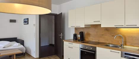 A compact kitchen with white cabinets, a wooden countertop, and modern appliances including a coffee maker and a dishwasher.