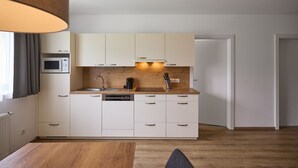 A modern kitchen with white cabinets, a microwave, a dishwasher, and a wooden countertop. - 4805 Cirrus 5 (St. Gallenkirch)