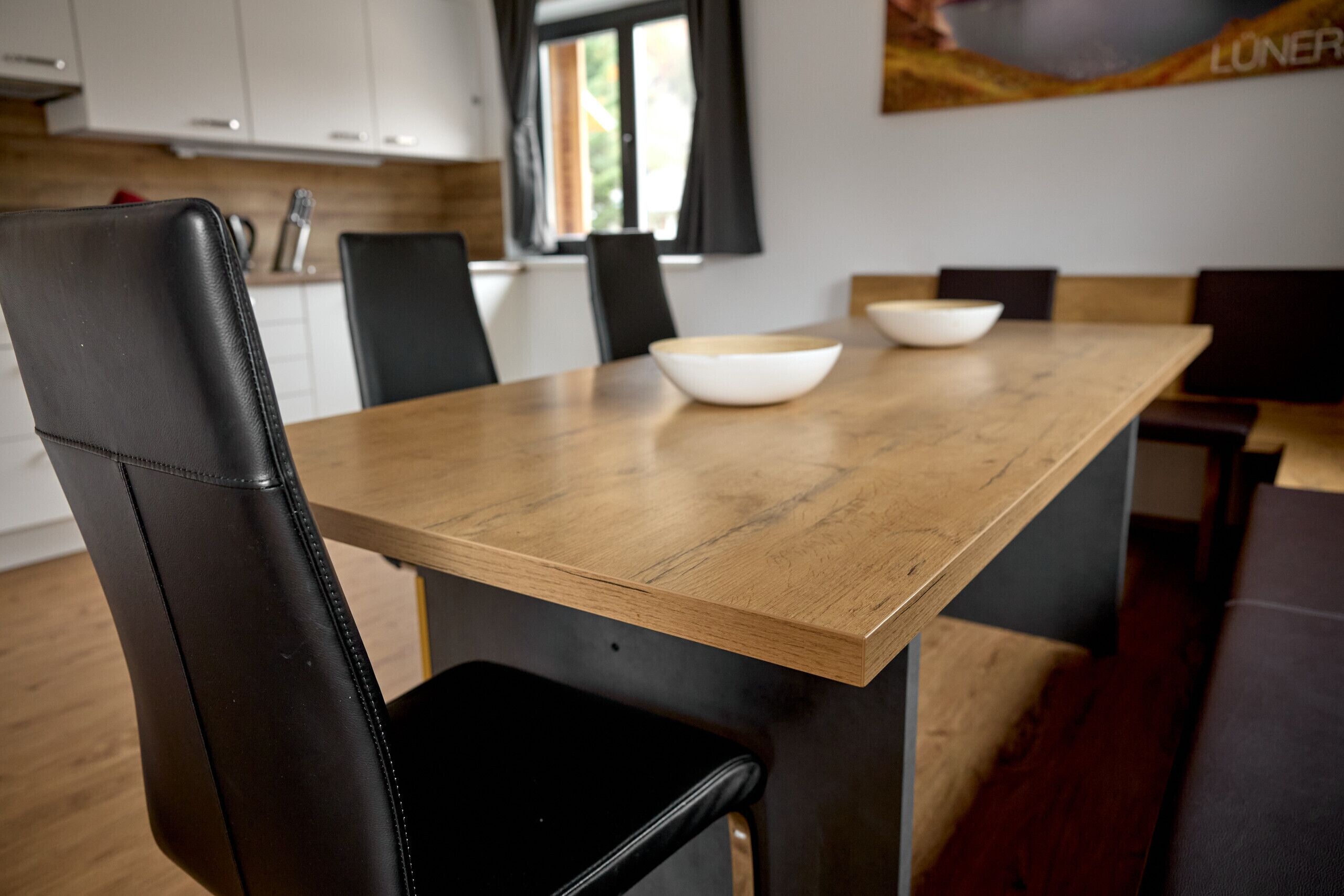 A dining area with a wooden table and black leather chairs.
