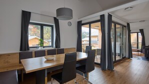 A modern dining area with a wooden table, black chairs, and a large window with curtains. - 46142 Montan 14 OG (St. Gallenkirch)