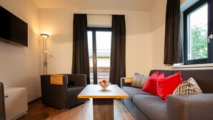 Un salon moderne avec un canapé, une table basse et un téléviseur fixé au mur.