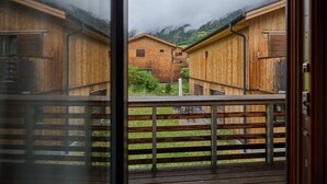 A wooden building with a balcony, a view of the surrounding area, and a mountain in the background.