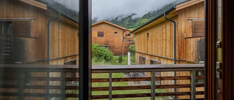 A wooden building with a balcony, a view of the surrounding area, and a mountain in the background.