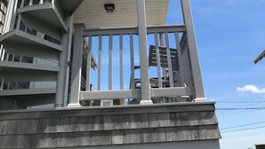 Ein Gebäude mit weißer Fassade, einem Balkon mit weißem Geländer und einer Wendeltreppe.