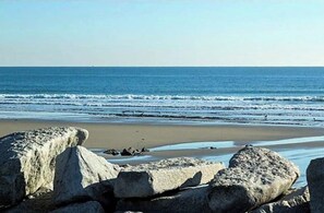 A beach with large rocks in the foreground and waves in the background. - Boathouse Apartment at Fortunes Rocks, 100 feet from the beach. (Biddeford)