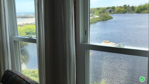 Blick durch ein Fenster auf einen Fluss und grüne Umgebung.