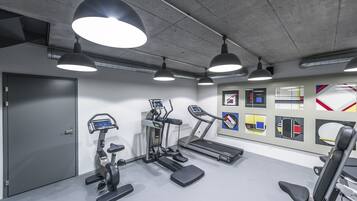 Un gimnasio con cintas de correr, elípticas y una bicicleta estática.