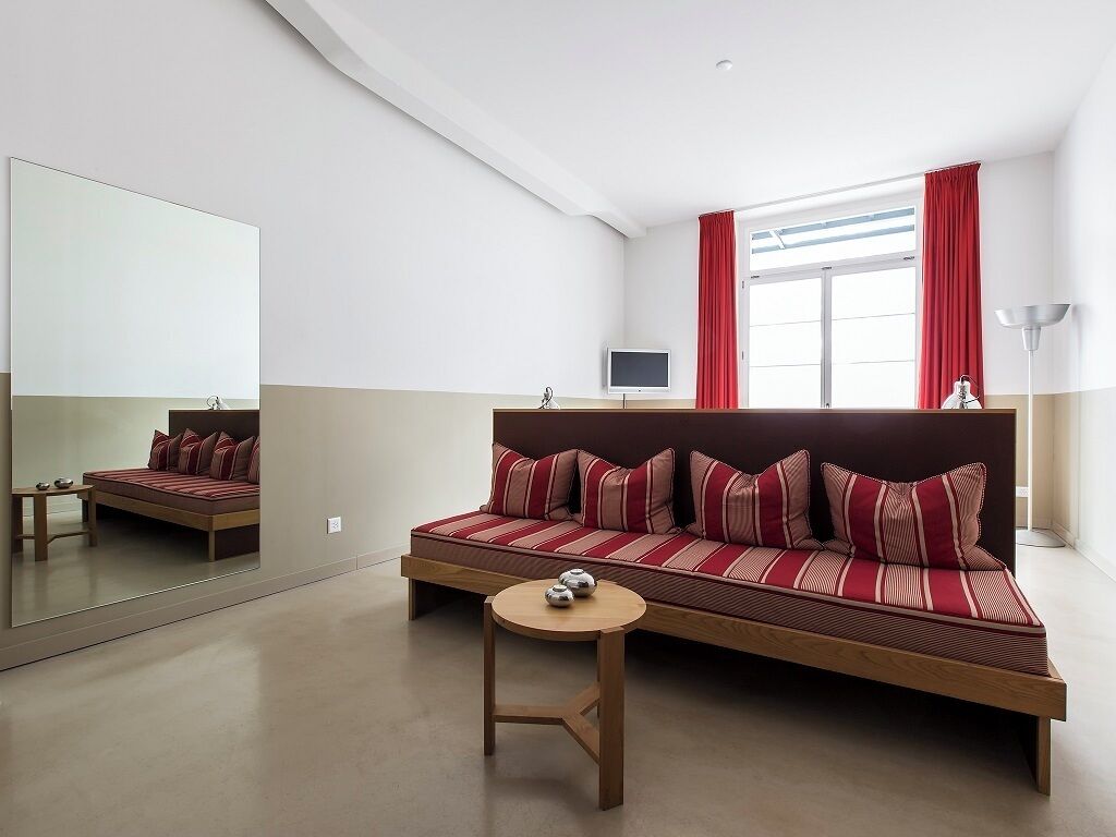 A modern room with a sofa, a small table, a TV, and a large mirror.