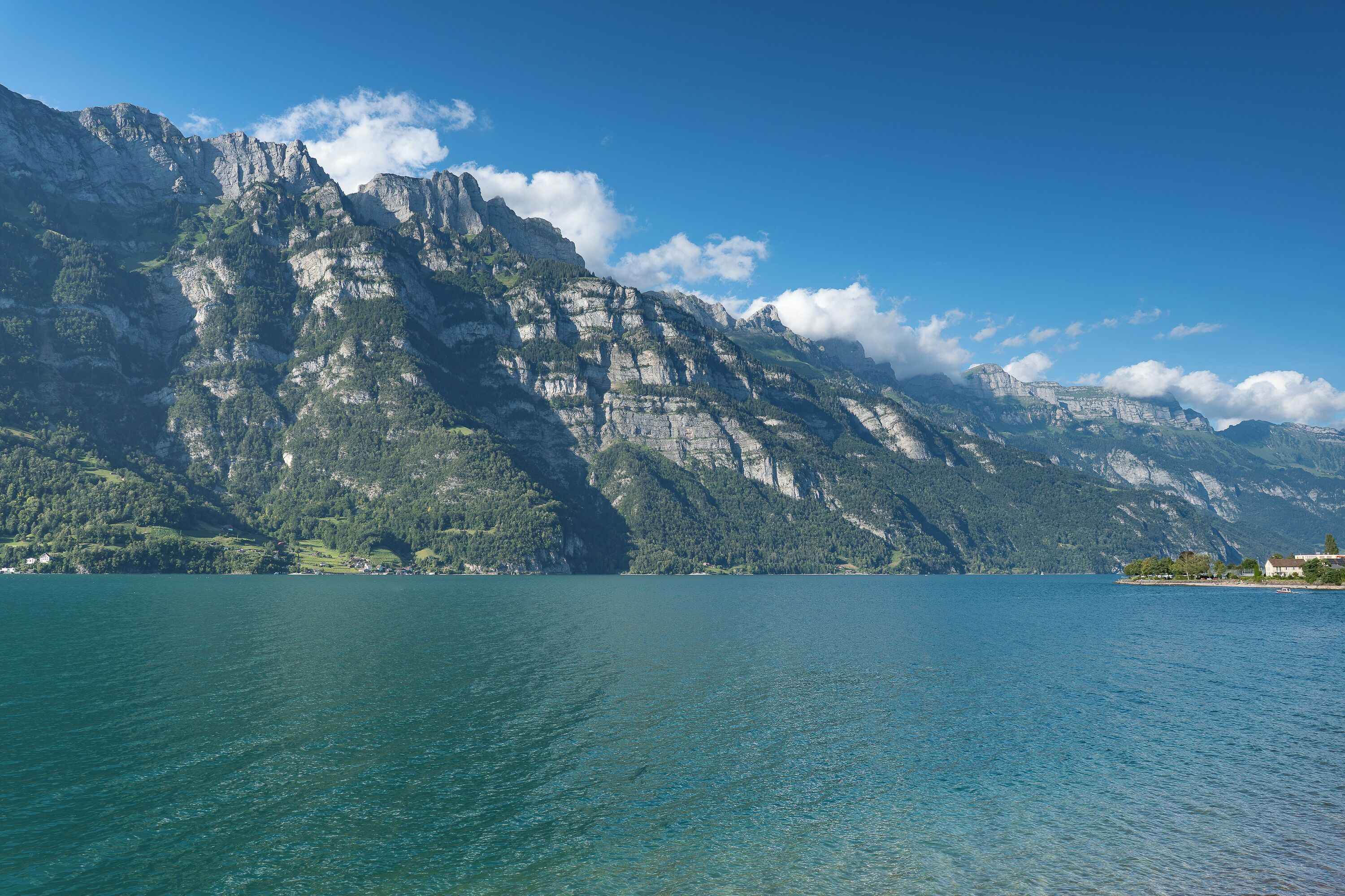 Un paisaje montañoso con un lago y un edificio pequeño en la orilla.