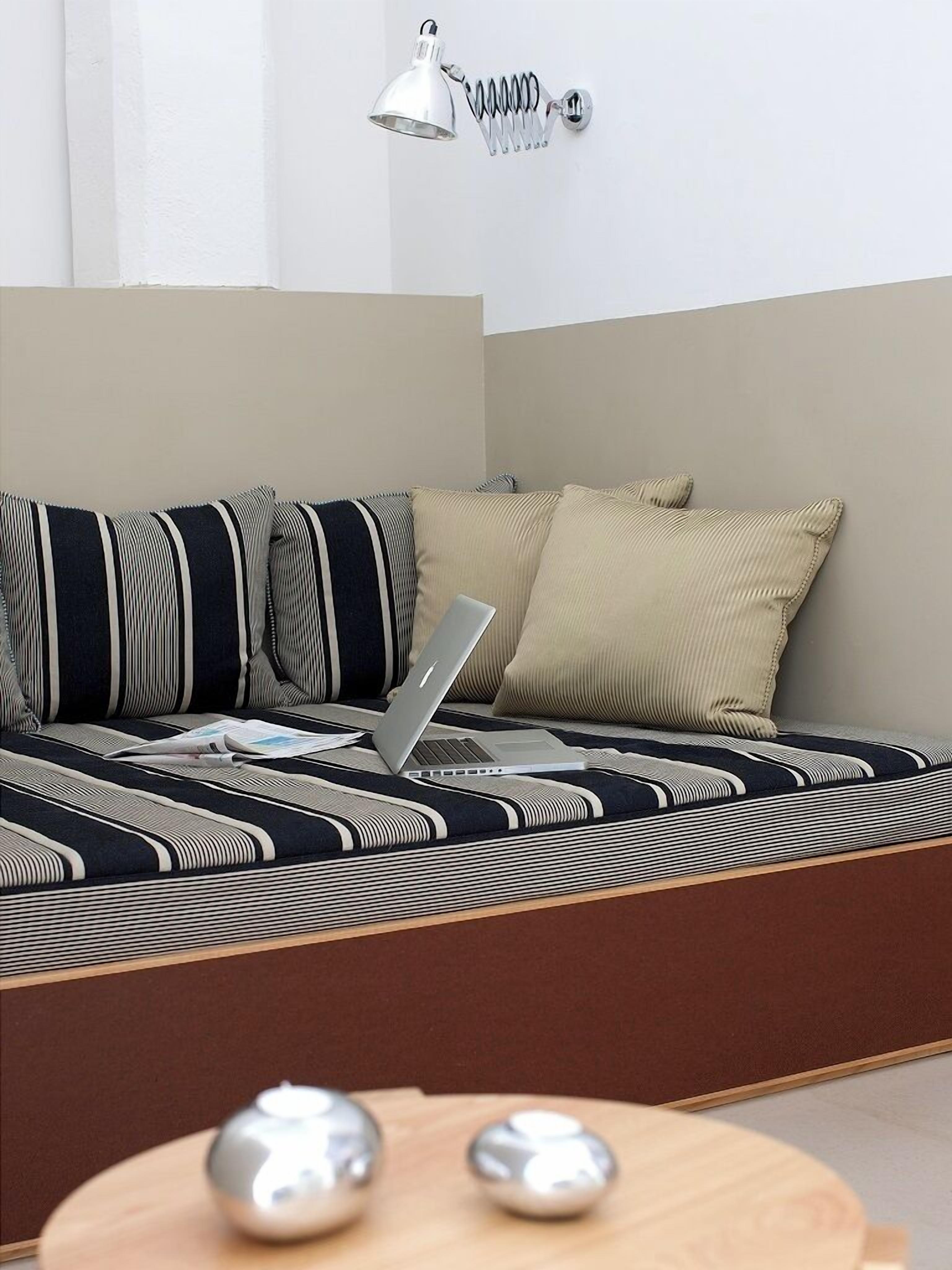 Ein modernes Zimmer mit einer Couch, einem Laptop und einer Wandleuchte.
