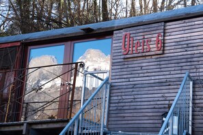 A wooden building with a sign reading 'Gleis 6' and a metal staircase leading to a window overlooking a mountain.