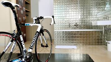 A bicycle in a bathroom with a tiled wall, a sink, and a mirror.