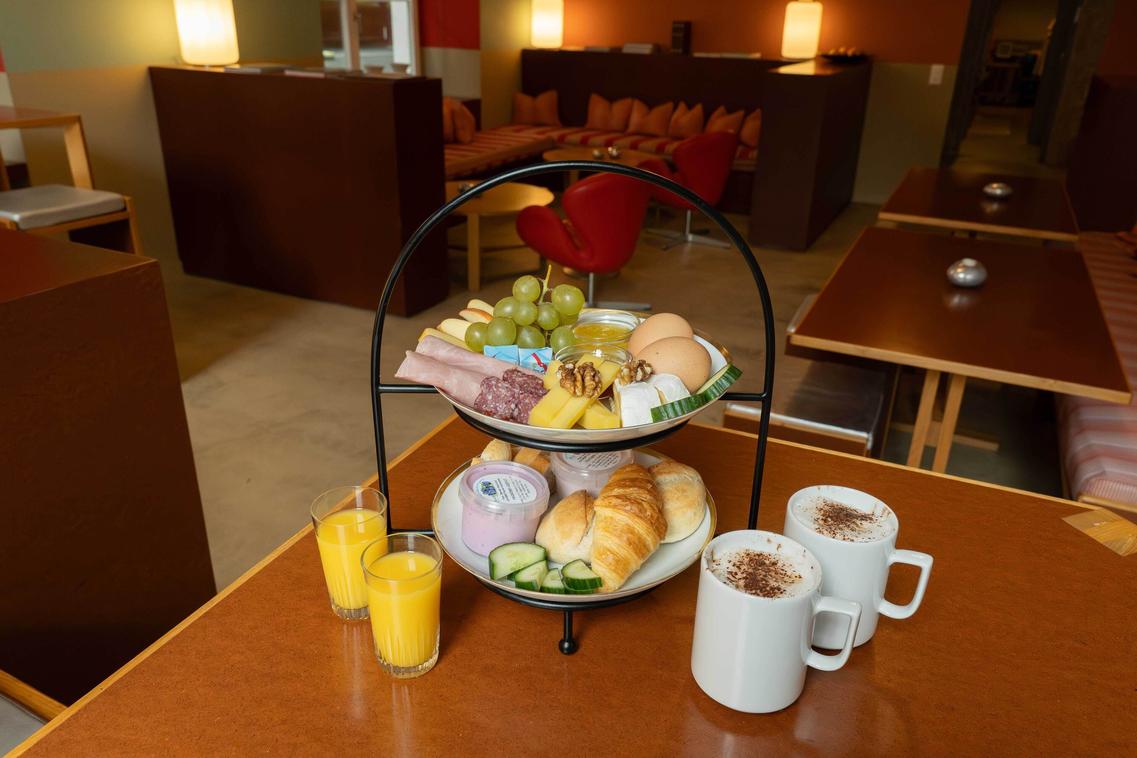 A breakfast buffet with fruits, cheeses, and pastries, along with juice and coffee.