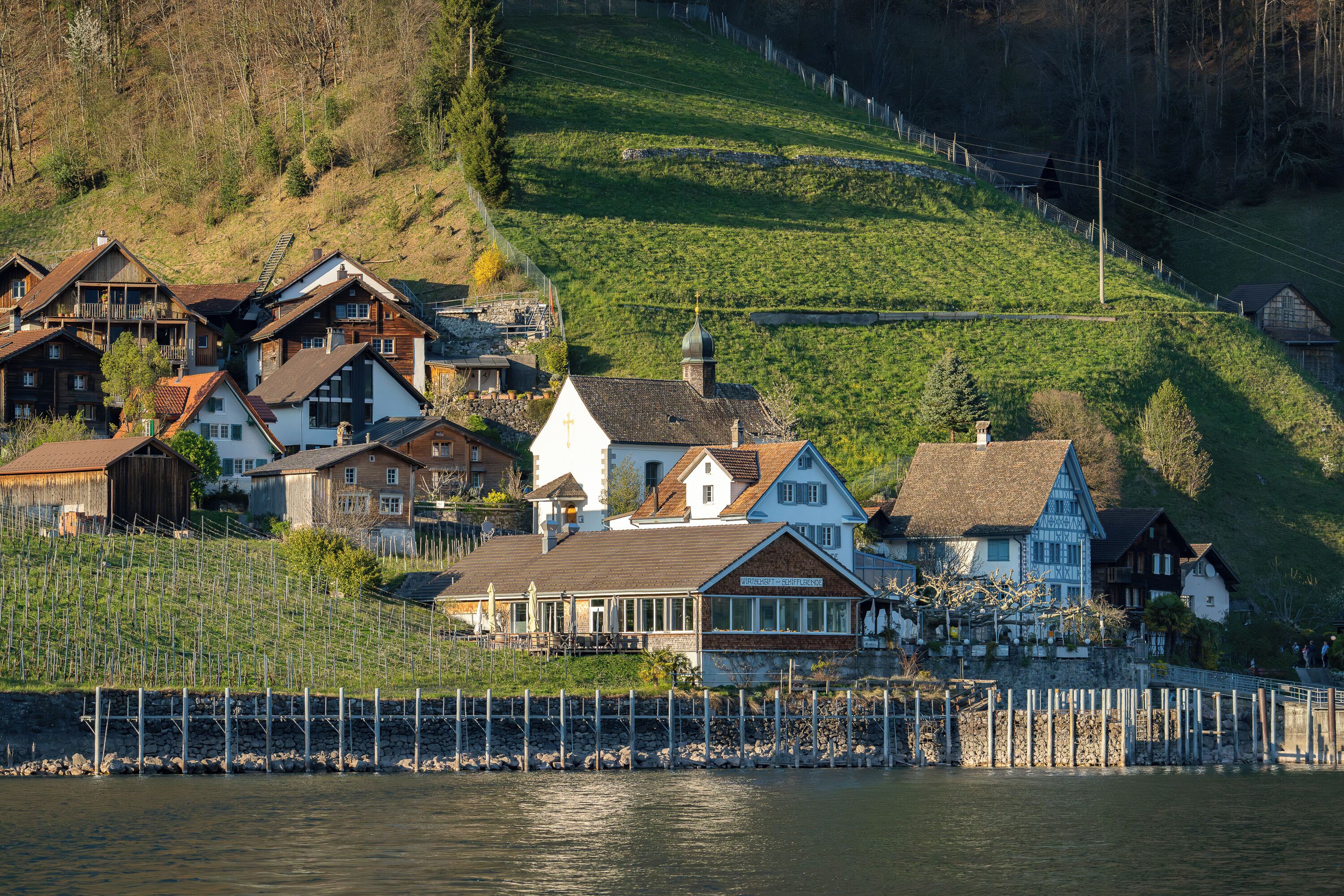 A lakeside village with traditional houses, a church, and a bridge.