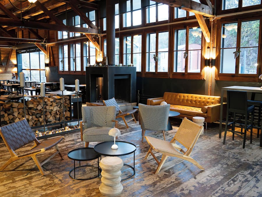 A rustic interior with a fireplace, wooden furniture, and large windows.