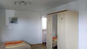 A room with a bed, a wardrobe, and a chair. - Ferienwohnung, 35 qm Erdgeschoss, Kombinierter Wohn- und Schlafraum (Bad Endorf)