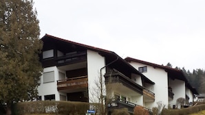A two-story residential building with balconies, a sign indicating a no parking zone, and a grassy area in front. - Ferienwohnung, 35 qm Erdgeschoss, Kombinierter Wohn- und Schlafraum (Bad Endorf)