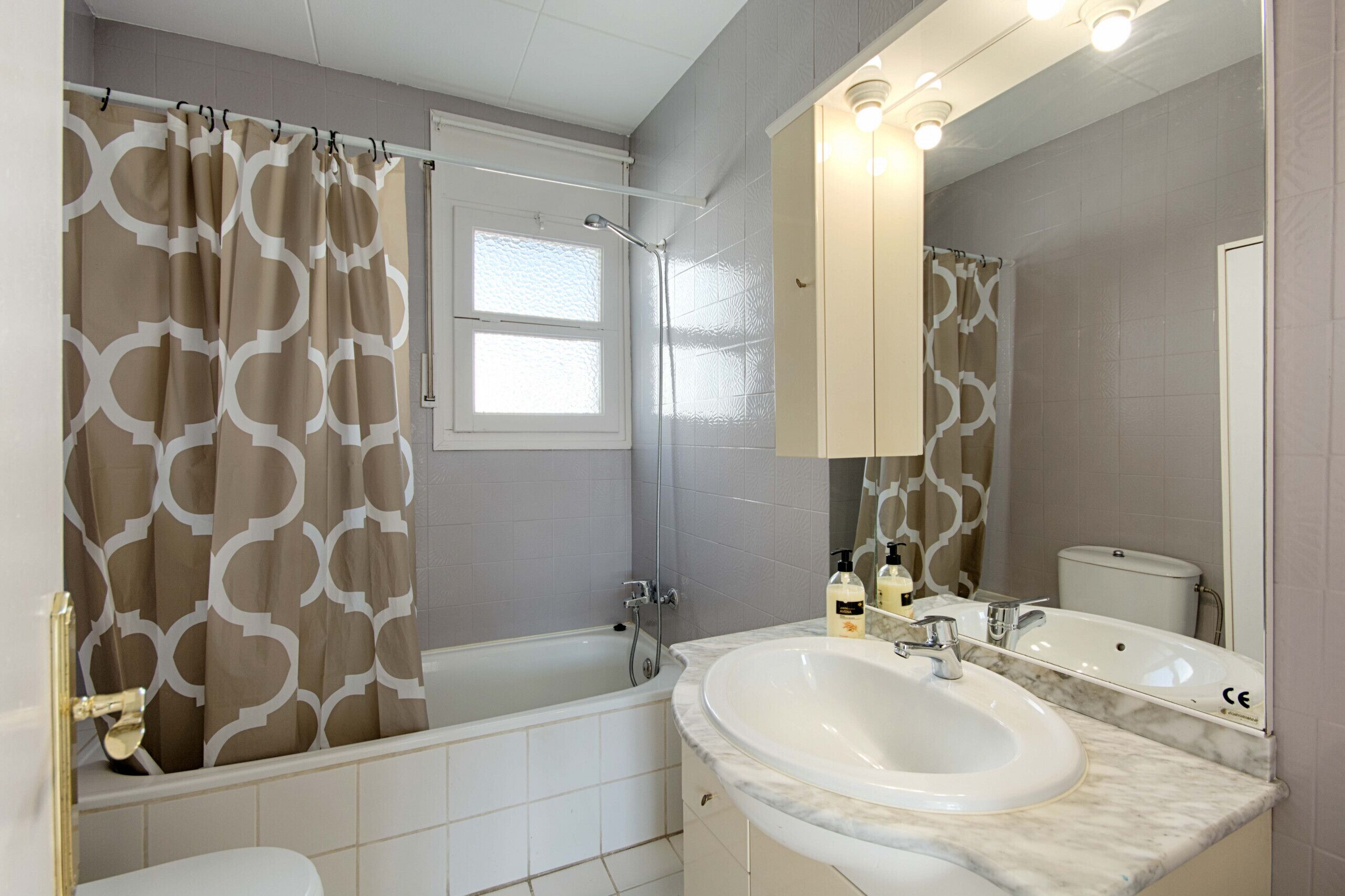 A bathroom with a bathtub, shower, toilet, and a large sink with a mirror above it.