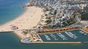 An aerial view of a coastal city with a beach, marina, and dense urban area with high-rise buildings. - Ocean Breeze (Portimão)