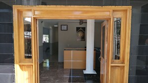 A hotel lobby with a wooden frame entrance, a reception desk, a clock, and a pillar. - Hotel Yamir (Barahona)