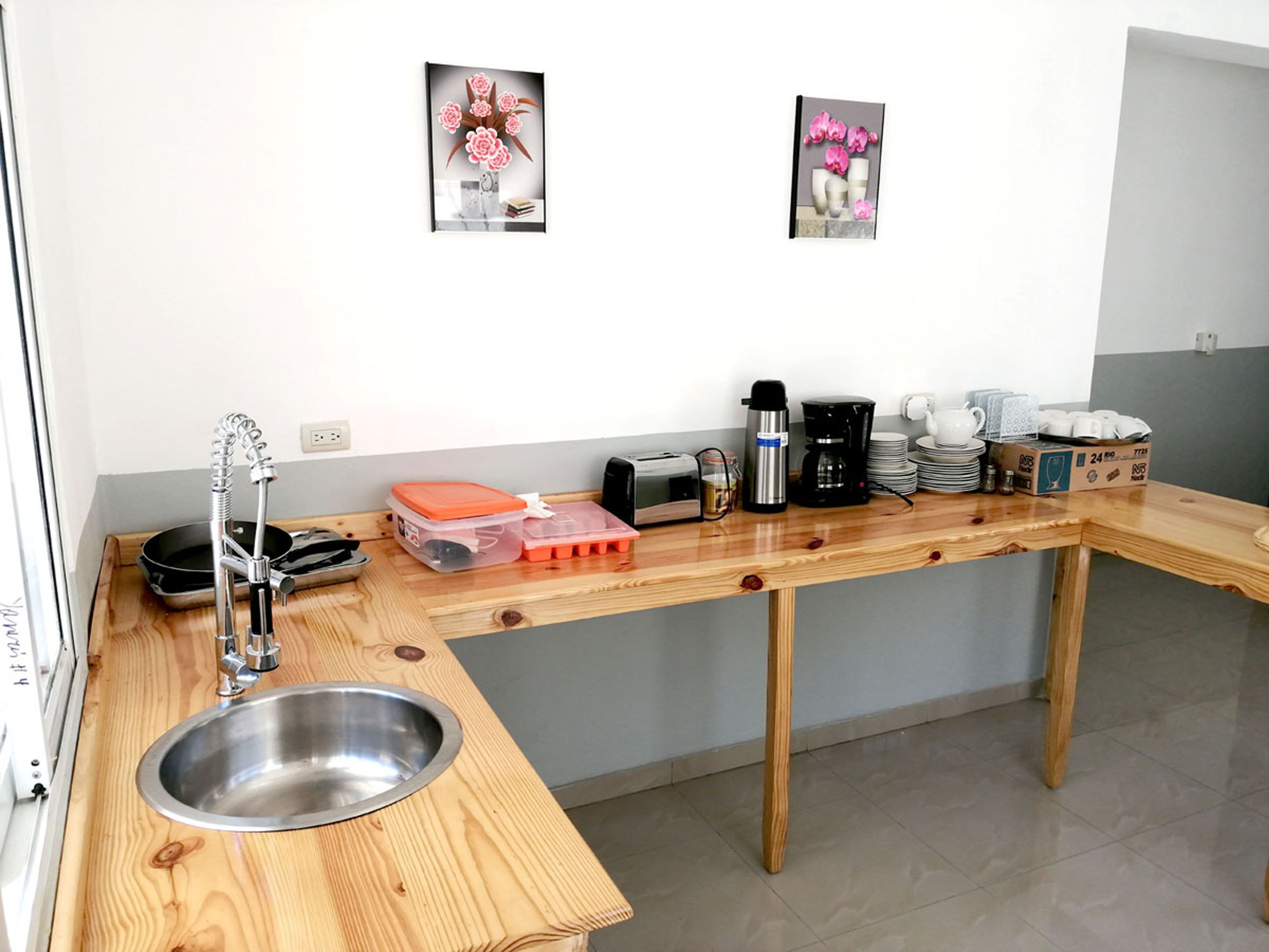 Una cocina con encimera de madera, pileta de acero inoxidable y diversos electrodomésticos, incluyendo una tostadora y una cafetera.