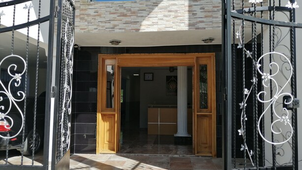 A gated entrance with a wooden door and a stone wall. - Hotel Yamir (Barahona)