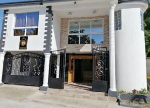 A modern hotel entrance with a black and white facade, a prominent logo, and a gated entrance with decorative ironwork. - Hotel Yamir (Barahona)
