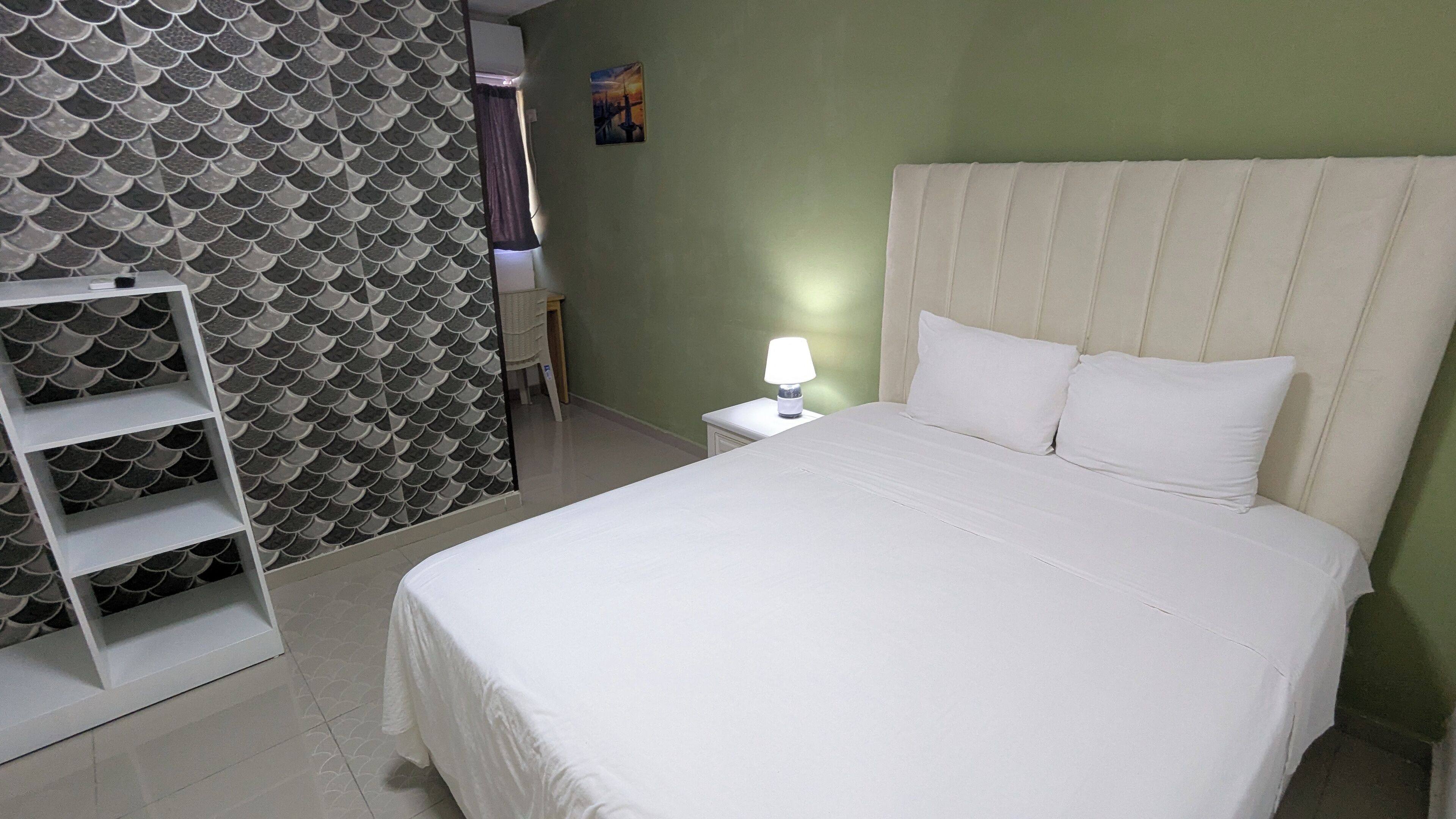 Un lit bien fait, avec du linge de lit blanc, une lampe de chevet et un mur orné d’un motif en forme d’écailles de poisson.