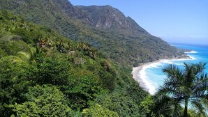 A coastal landscape with a beach and dense green hills. - Hotel Yamir (Barahona)