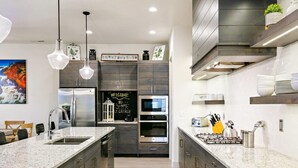 A modern kitchen with granite countertops, stainless steel appliances, and dark wood cabinetry.