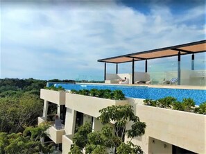 A modern building with a rooftop pool and outdoor seating area. - Aldea Zama- Studio Condo, with Rooftop Pool  (Tulum)