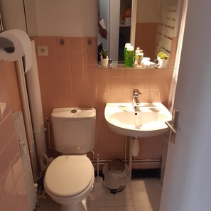 Een bad/douchecombinatie, een haardroger, badjassen, handdoeken