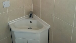 A corner bathroom with a white sink, a mirror, and a cabinet with two drawers. - Glen Villa Flat 3 - 4 Berth (Great Yarmouth)