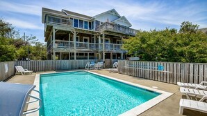 A two-story building with a swimming pool, wooden deck, and outdoor seating area. - Seaside Memories | 930 ft from the beach | Private Pool, Hot Tub (Nags Head)