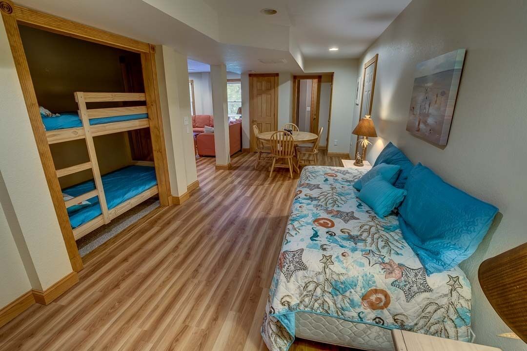 Une chambre avec des lits superposés, un canapé avec des coussins à motifs, une table à manger avec des chaises et une lampe.