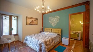 Quarto com cama, cadeira, escrivaninha e um coração decorativo na parede.