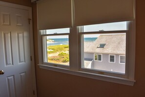 A room with a door and two windows overlooking a beach and a building.