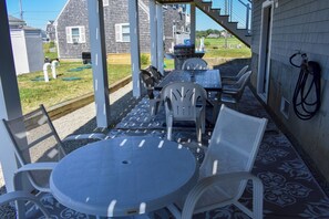 An outdoor patio with a table and chairs, a grill, and a hose on the wall.