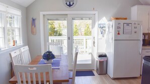 A kitchen with a wooden table, white chairs, a white refrigerator, and a door leading to a balcony.
